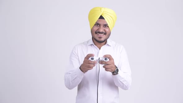 Happy Bearded Indian Sikh Businessman Playing Games and Winning