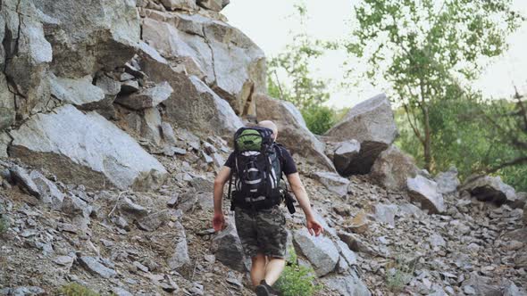 A traveler with a backpack on his shoulders rises to the top of the mountain with stones