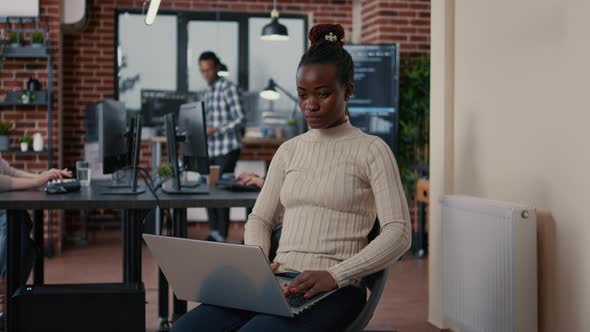 Portrait of African American Programer Sitting Down Coding on Laptop Looking Up and Smiling