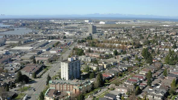 Aerial flying over South Vancouver toward the YVR airport as a plane flies in to land.