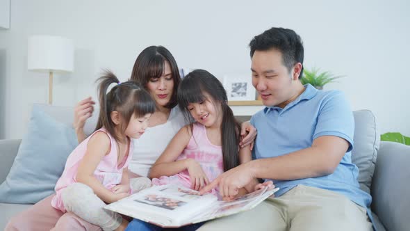 Asian family looking at photographs on old picture album recalls the past.