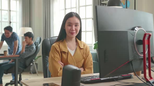 Asian Female Works Her Personal Computer. She Turns And Warmly Smiles Into The Camera