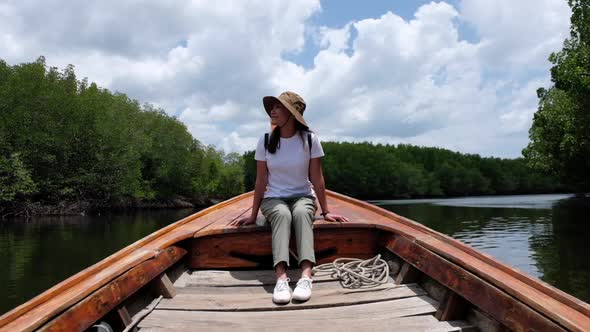 A beautiful young asian woman sitting on a long tail boat while traveling the mangrove forest