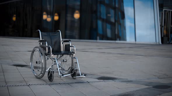 Invalid Wheelchair Rolling Near Modernn Building.