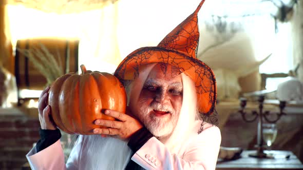Halloween Old Man with Pumpkin in Hand. Bearded Man Ready for Halloween Party. Evil Wizard Hold