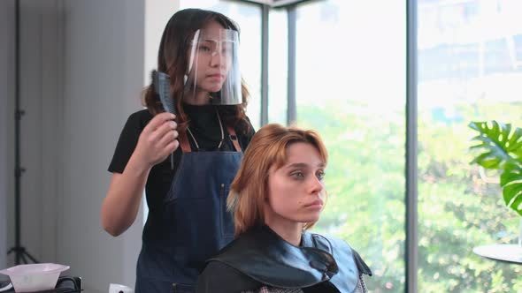 Asian beauty salon barber woman start the process of dye to Caucasian customer hair