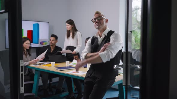 Portrait of Confident Satisfied Male CEO in Eyeglasses with Mohawk Haircut Crossing Hands Looking at