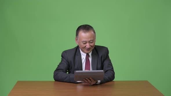 Mature Japanese Businessman Working with Digital Tablet