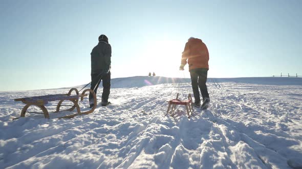 Active Seniors Walking up Hill With Winter Sledges