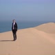 A Young Man Walks Along Sandy Dunes on the Seashore - VideoHive Item for Sale