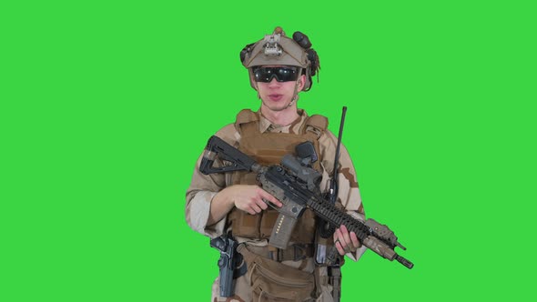 Smiling Soldier with Assault Rifle Talking on a Green Screen, Chroma Key