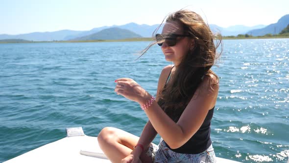 Young Woman Sitting on Bow of Boat and Admiring Beautiful Nature Landscape During Trip. Pretty Girl