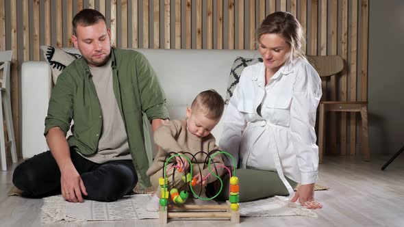 Little Boy Plays with Puzzle Game Sitting Near Parents