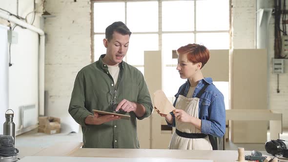 Man and Woman with Digital Tablet Working Together Cooperating in Workshop