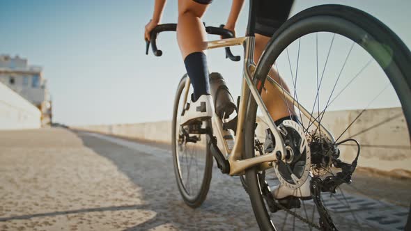 Legs of Unrecognizable Young Lady in Cycling Shoes and Sportswear Who is Riding a Bicycle Along Sea