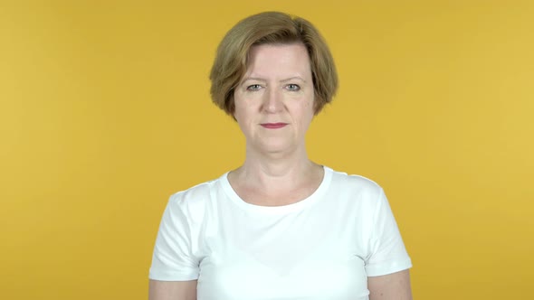 Old Woman Pointing at Camera Isolated on Yellow Background