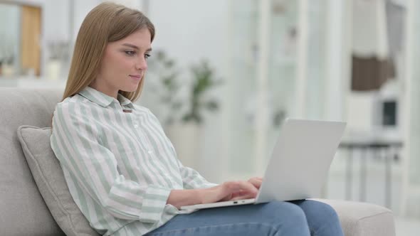 Focused Young Woman Working on Laptop at Home