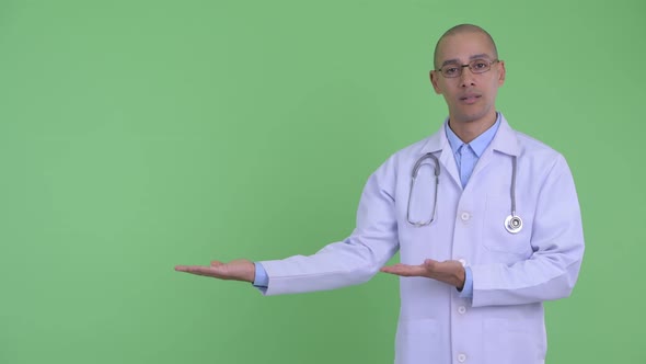 Stressed Bald Multi Ethnic Man Doctor Showing Something