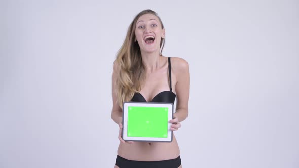 Happy Blonde Woman in Bikini Showing Digital Tablet and Looking Surprised