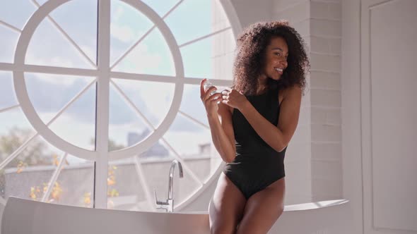 Happy Afro Woman Takes Care of Her Hair After Bath Spraying Hairspray