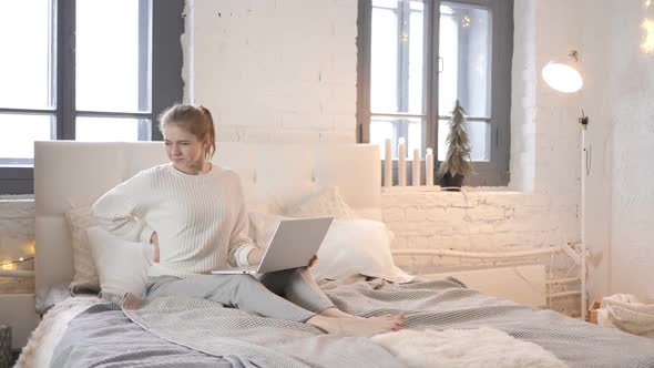 Young Girl with Back Pain Working on Laptop in Bed