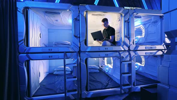 Capsule Hotel with a Man Using a Laptop in One of the Rooms