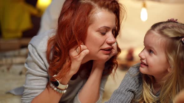 Front View Portrait of Beautiful Mother Kissing Nose of Cute Daughter Laughing