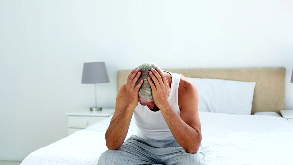 Hungover Man Sitting On The End Of His Bed 1