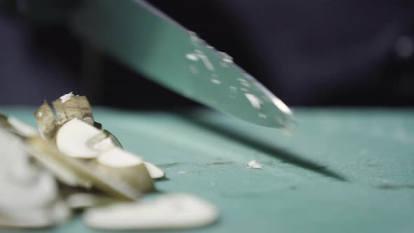 Cook's Hands in Black Gloves Slicing Mushrooms