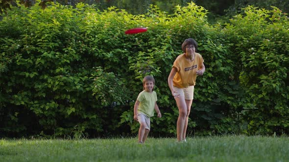Mother and Son Play Frisbee on Grass Lawn