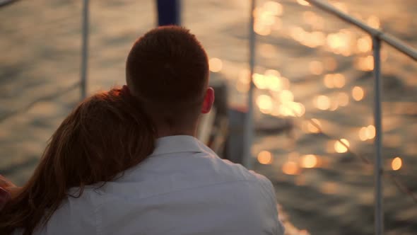 Woman Put Head on Men's Shoulder While Sitting on Front of Yacht Watching at Sea Backside in Slow