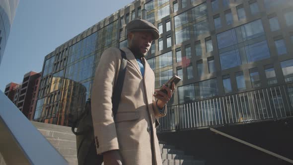 Afro-American Businessman Walking in City and Using Smartphone
