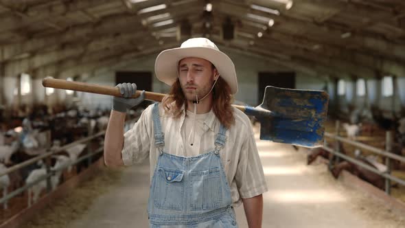 Man Holding Shovel on Shoulder While Walking at Goat Farm