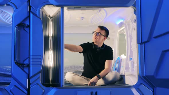 A Man Opens a Door of a Capsule Hotel Room From Inside