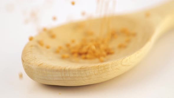 Mustard Seeds Strewed From Above Into a Wooden Scoop