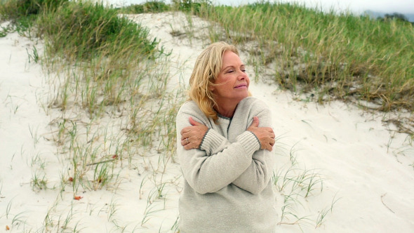 Smiling Retired Woman Shivering On The Beach