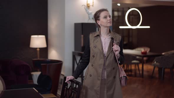 Curios Elegant Beautiful Woman Standing in Furniture Showroom Looking Around