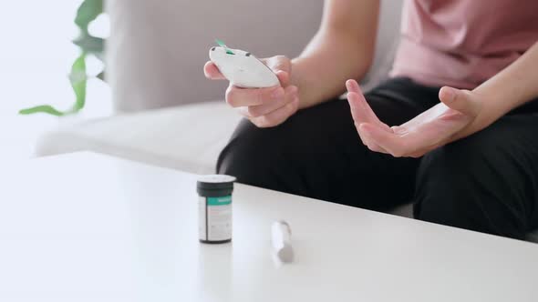 Asian woman checking blood sugar level by Digital Glucose meter