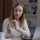Young attractive woman explaining something while pointing at her smartphone using app on laptop - VideoHive Item for Sale