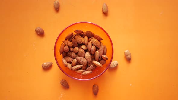 Top View of Almond Nuts in a Bowl on Orange Background