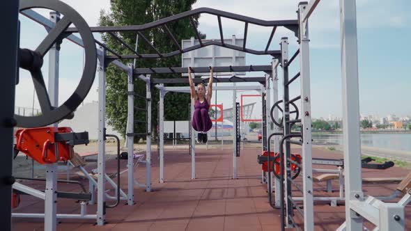 Young Athletic Woman Sports Purple Tracksuit Doing Abs Exercises Horizontal Bar