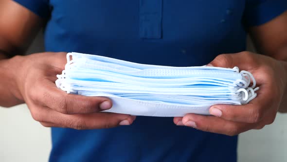 Man Hand Holding Stack of Surgical Face Mask Close Up