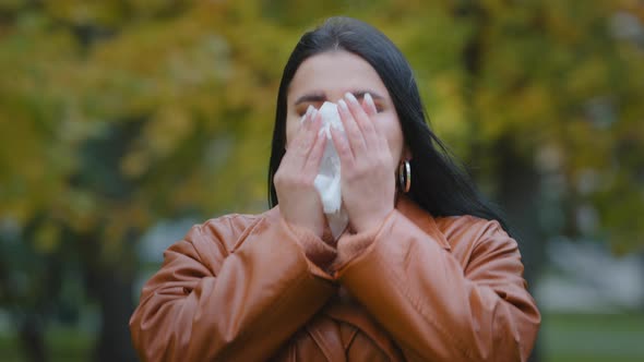 Young Ill Hispanic Woman Standing Outdoors Sneezing Into Handkerchief Wiping Nose Feeling Unwell