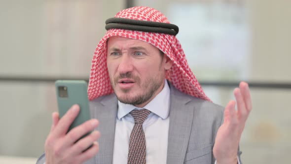 Portrait of Middle Aged Arab Businessman Reacting to Loss on Smartphone