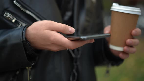 Closeup Smartphone in Hand of Young Caucasian Man Scrolling Social Media Standing Outdoors with