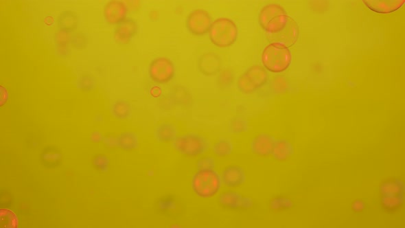 Soap Bubbles Lit By Red Neon Lights are Flying on a Yellow Background