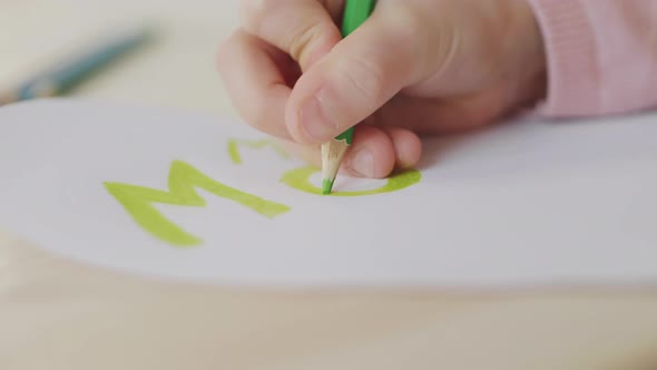 Child Drawing on Greeting Card with Green Pencil