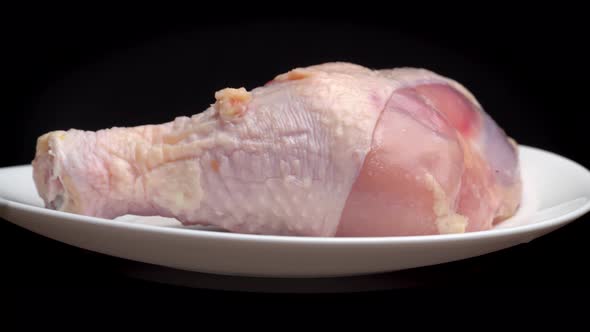 chicken leg or thigh with shin lies on white plate and rotates on turntable