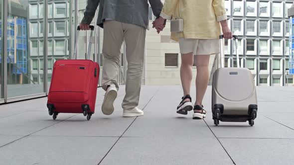 Rear View of a Mature Couple Walking with Suitcases Before Traveling to Travel at the Airport or