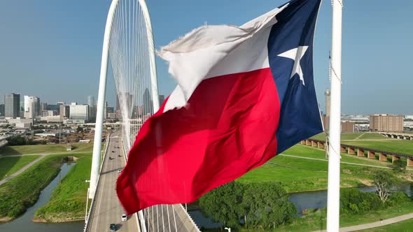 Texas Flag at Margaret Hunt Hill Bridge over Trinity River. Dallas Skyline. Rising aerial reveal on